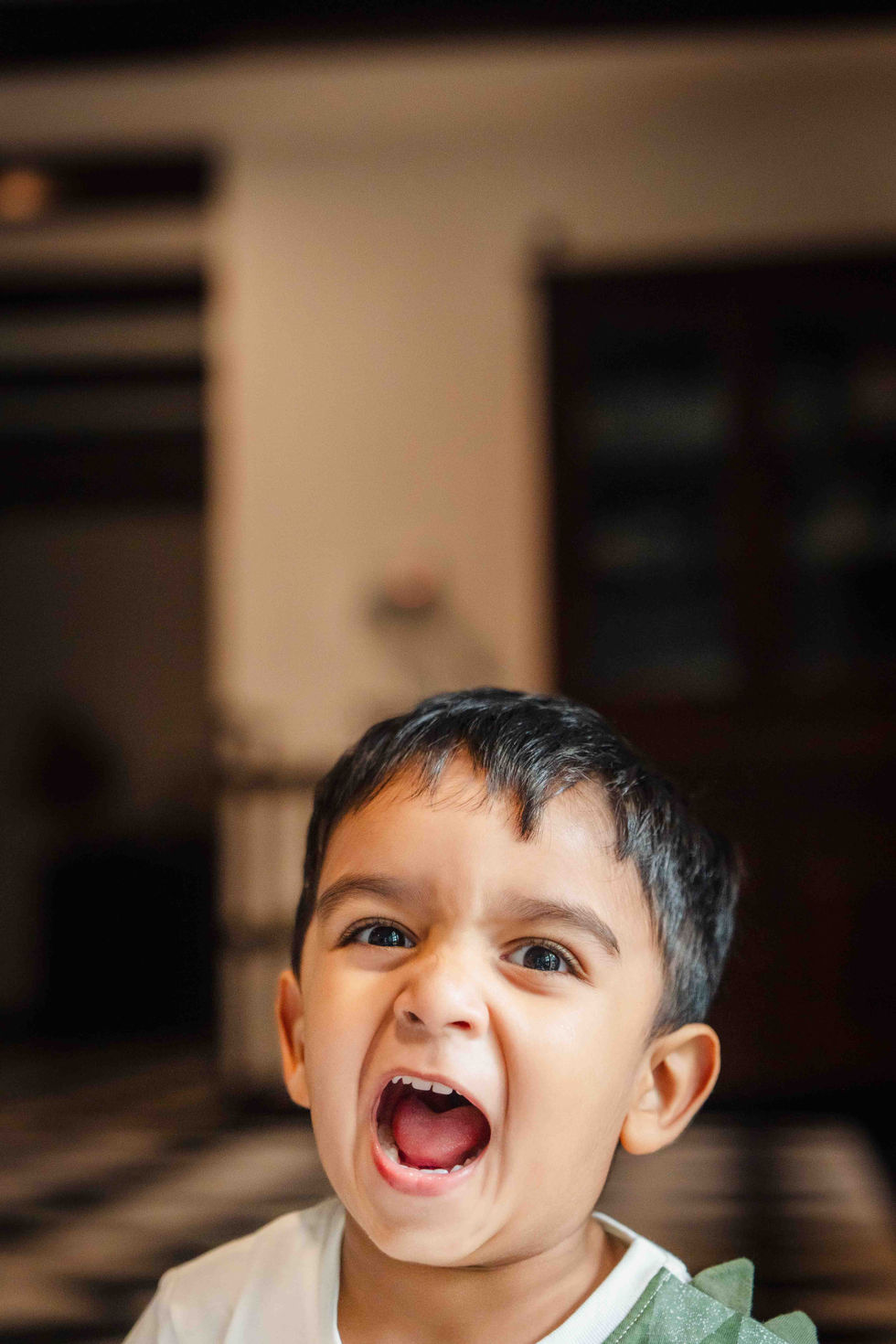 Child making a playful, expressive face indoors.