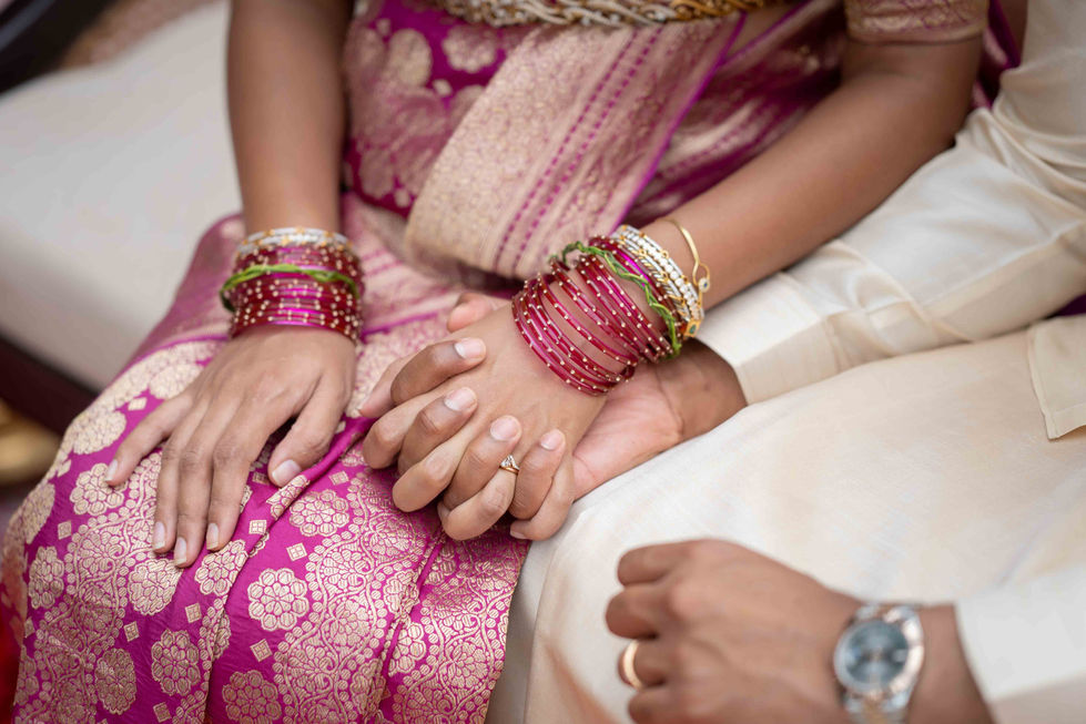 Couple holding hands, wearing traditional attire and bangles.