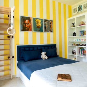 Bedroom with yellow striped walls and decorative shelves.