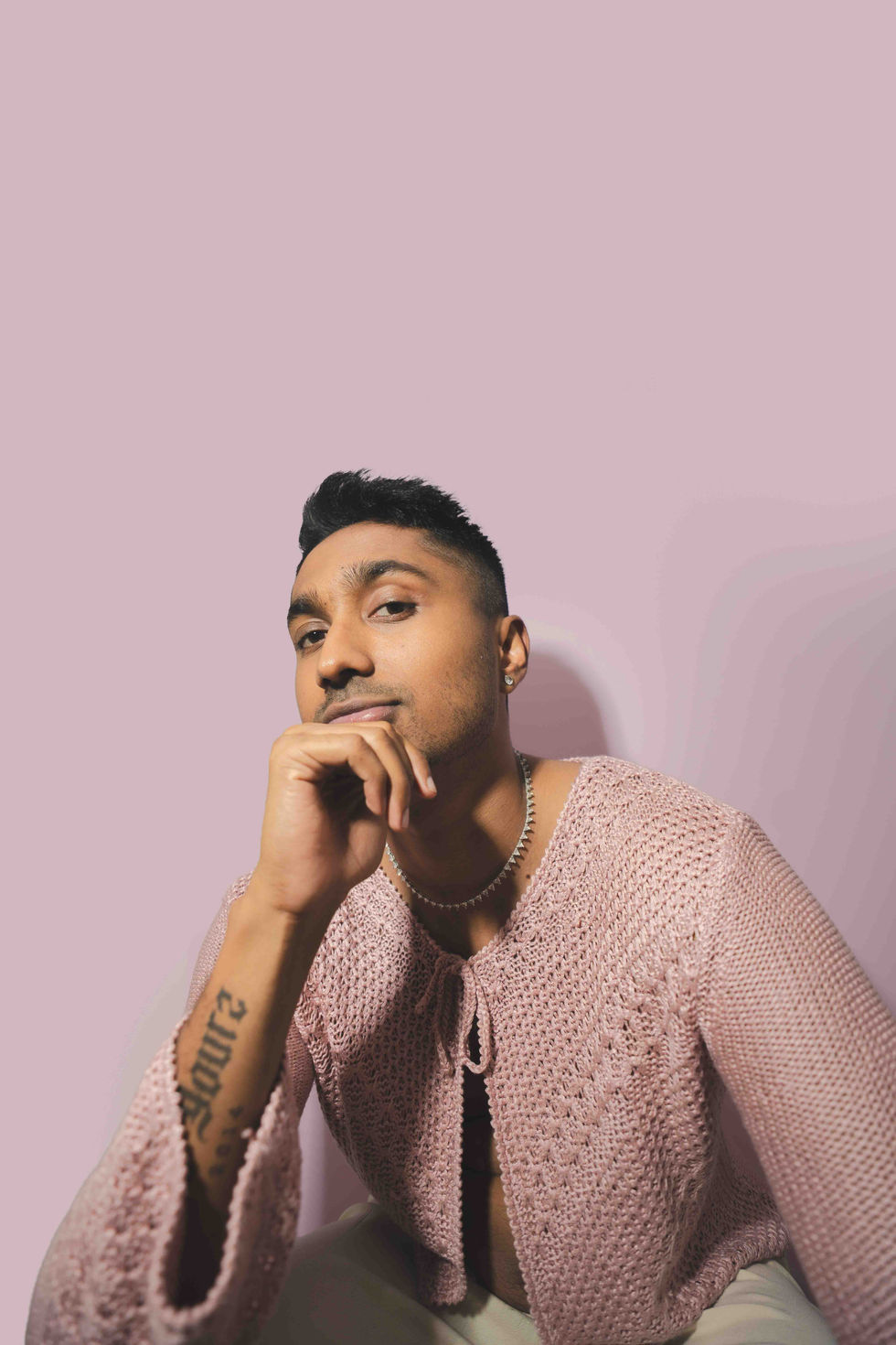 Person posing against a plain pink background.