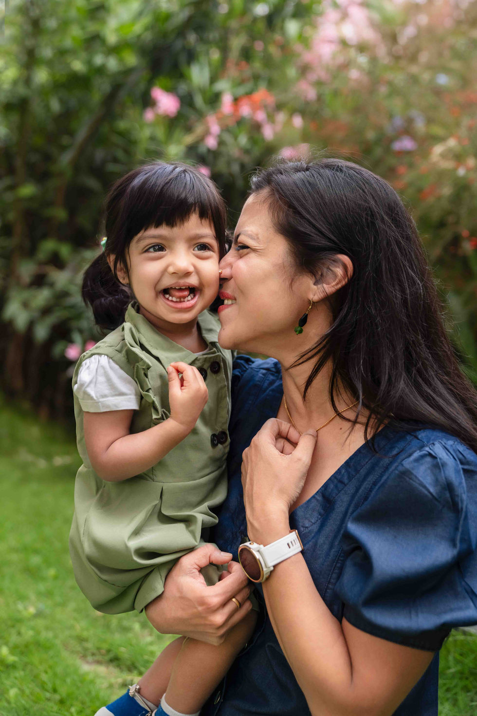 Mother and child smiling in a garden setting.