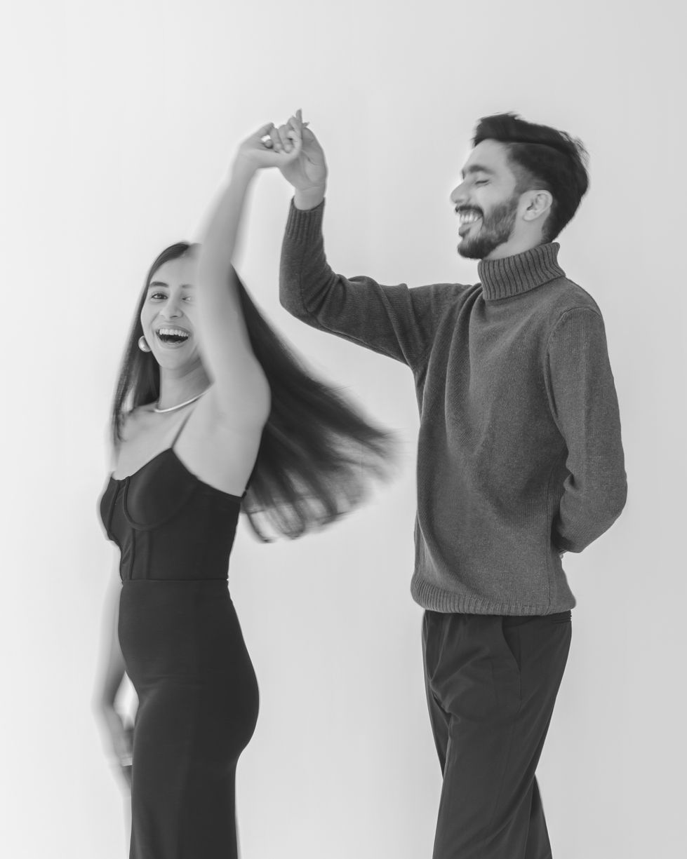 Couple dancing joyfully in black and white photo.