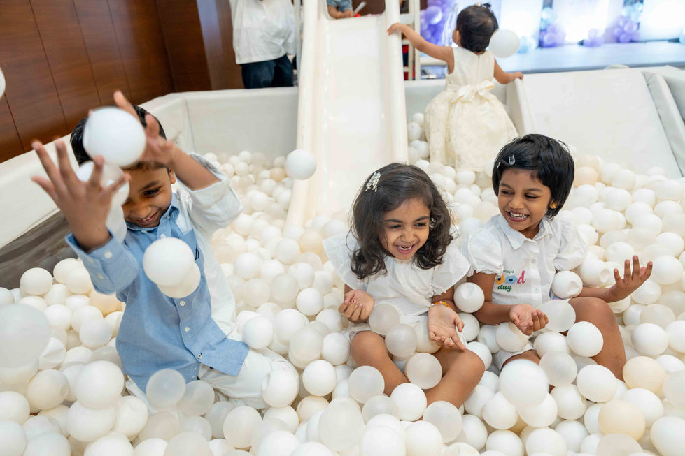 Children playing in a ball pit with white balls.