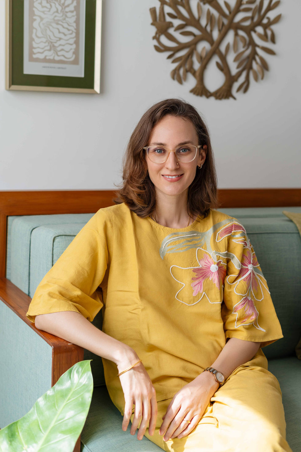 Ishani Lauren sitting on a couch, wearing yellow dress.