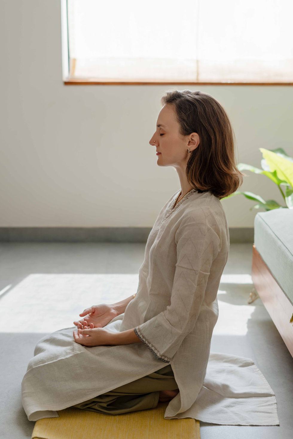 Ishani Lauren meditating indoors in peaceful setting.