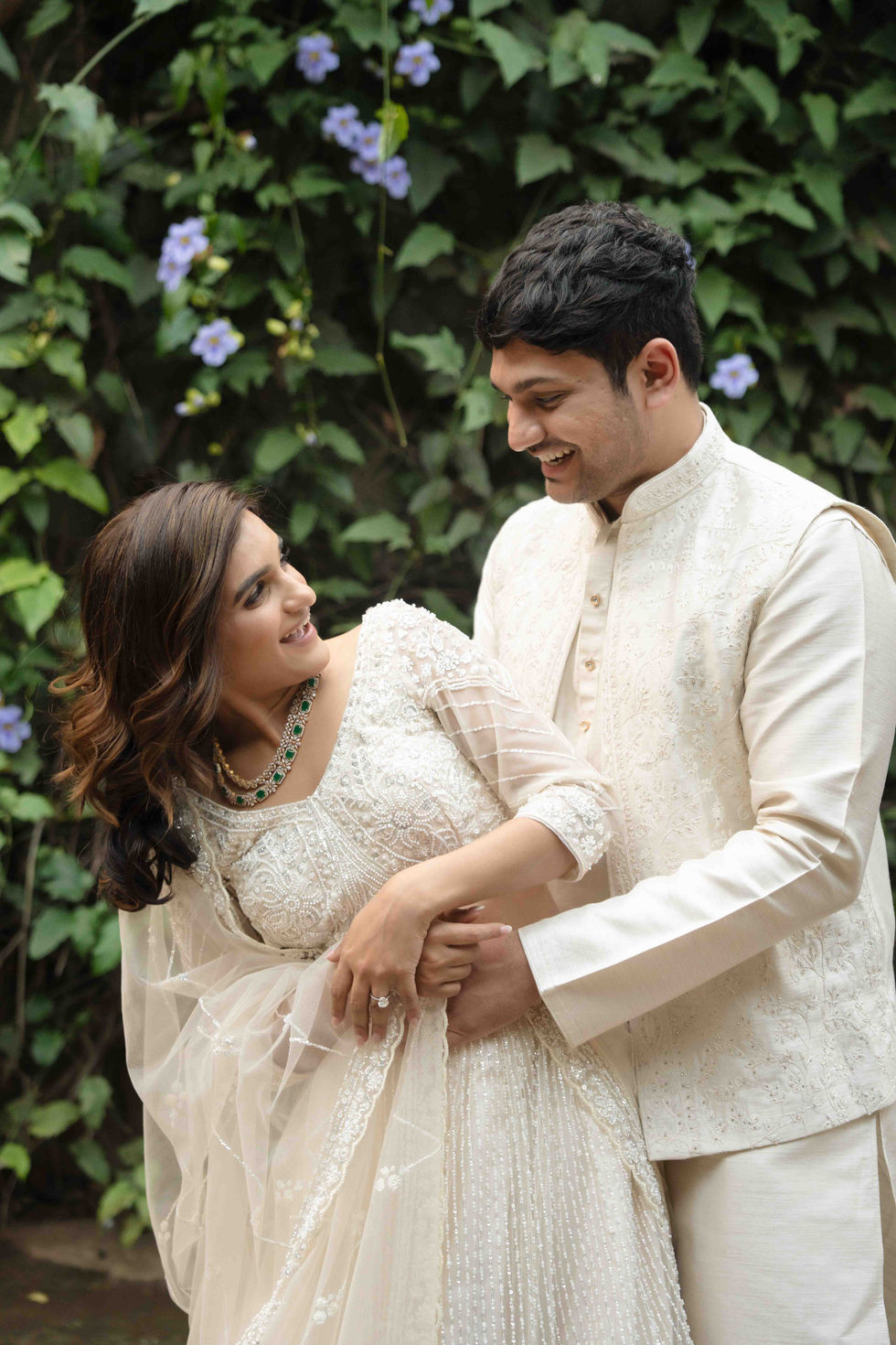 Bride and groom in traditional attire, smiling at each other.