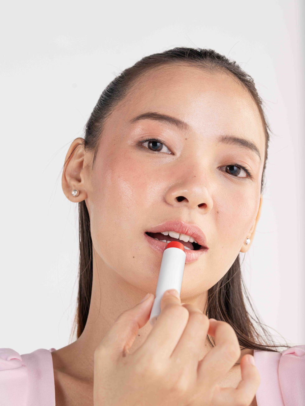 Woman applying SebaMed lip balm, close-up portrait.