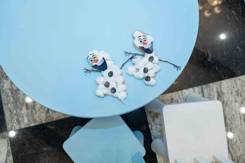 Two Olaf figures on a light blue table.