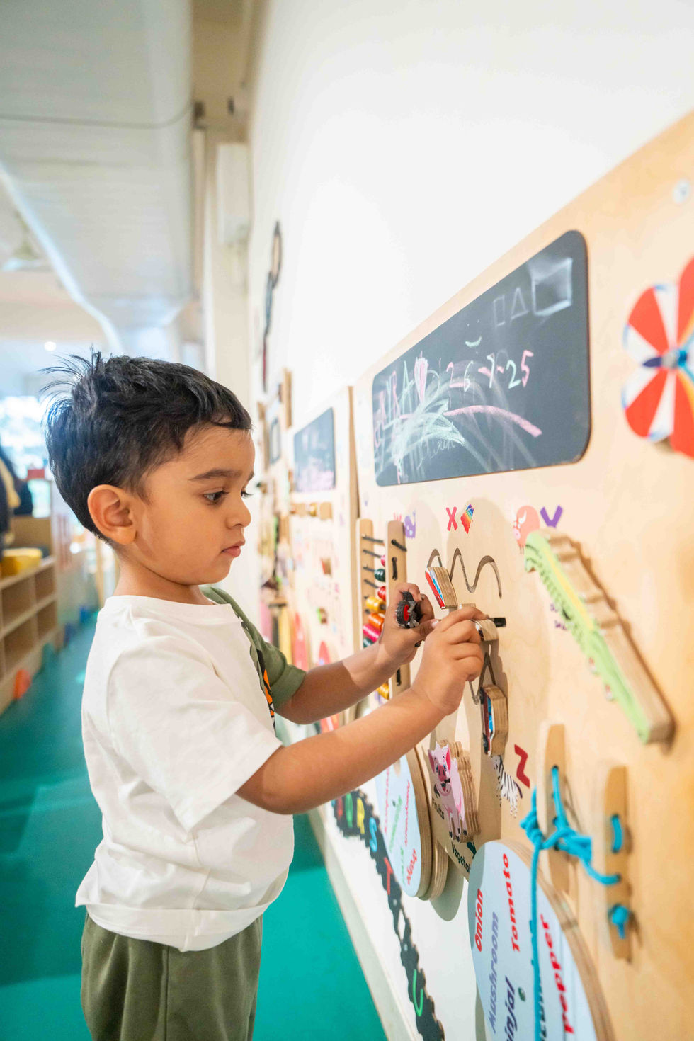 Child drawing on a classroom wall-mounted board.