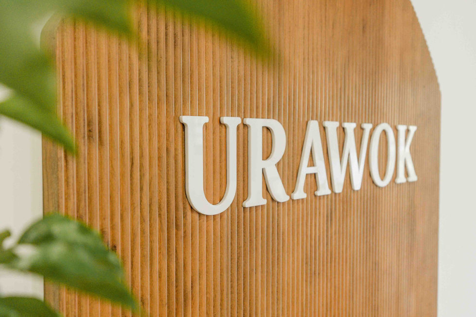 Text "URAWO" on wooden background with green leaves.