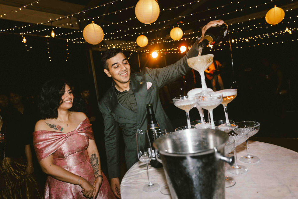 Man pouring champagne into tower at festive event.