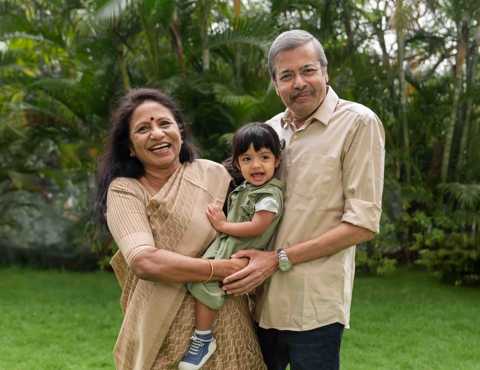 Smiling couple with child in a garden setting.