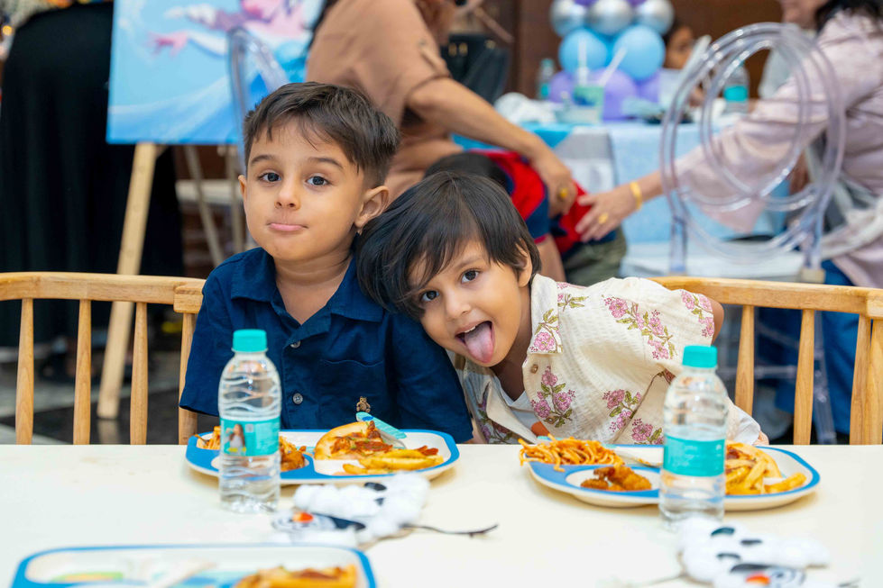 Two children making faces at a party table.