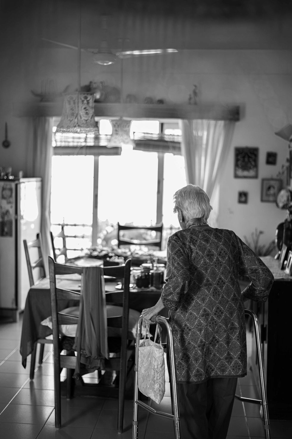 Elderly person with walker in a dining room.