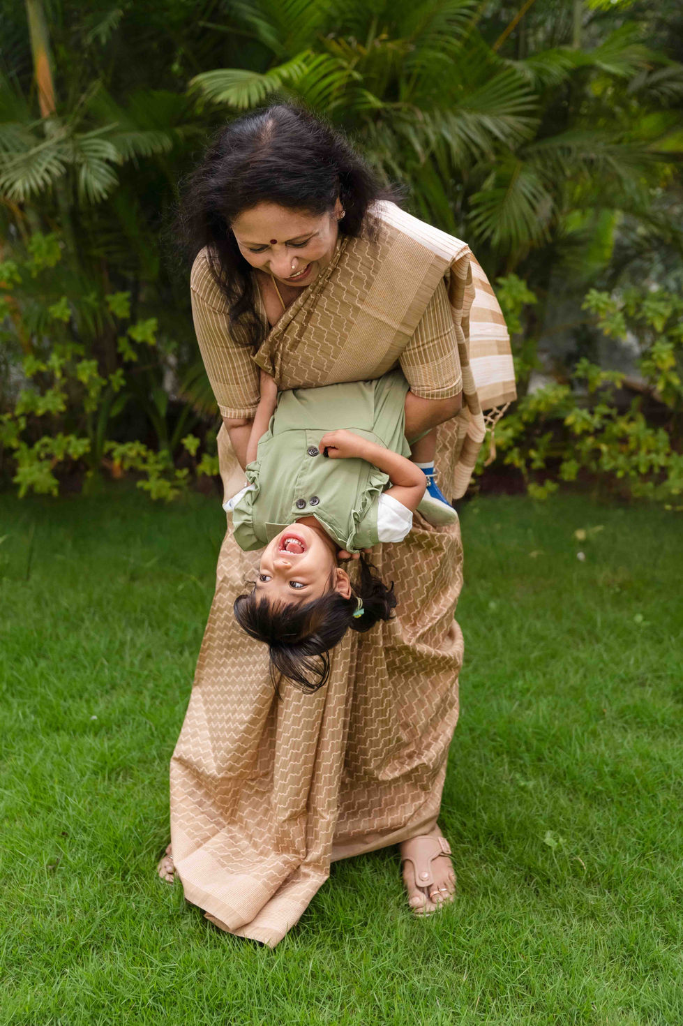 Woman joyfully playing with child on grass.