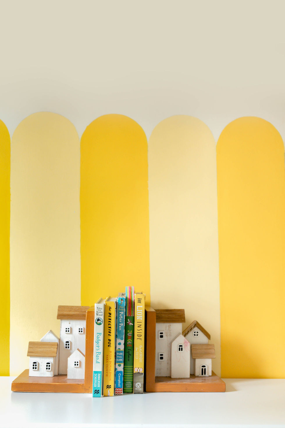 Books and wooden houses against yellow striped wall.