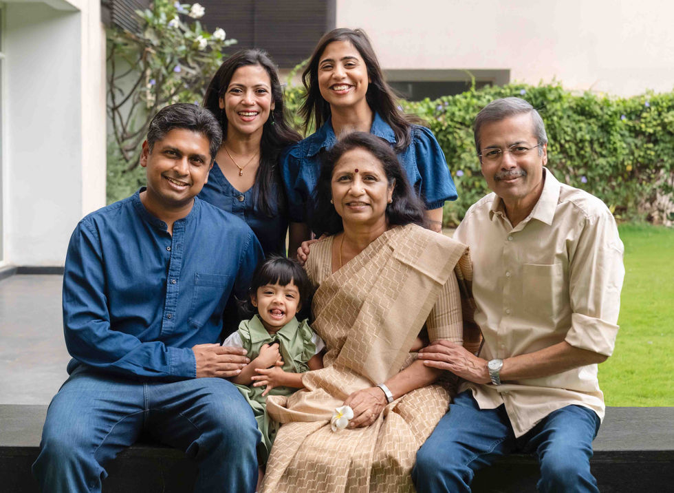 Family portrait with six smiling individuals outdoors.