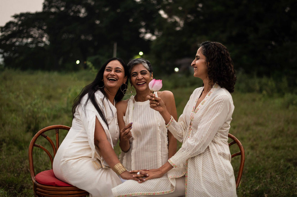 Three women in white kurtis from House of Anaar, smiling outdoors.