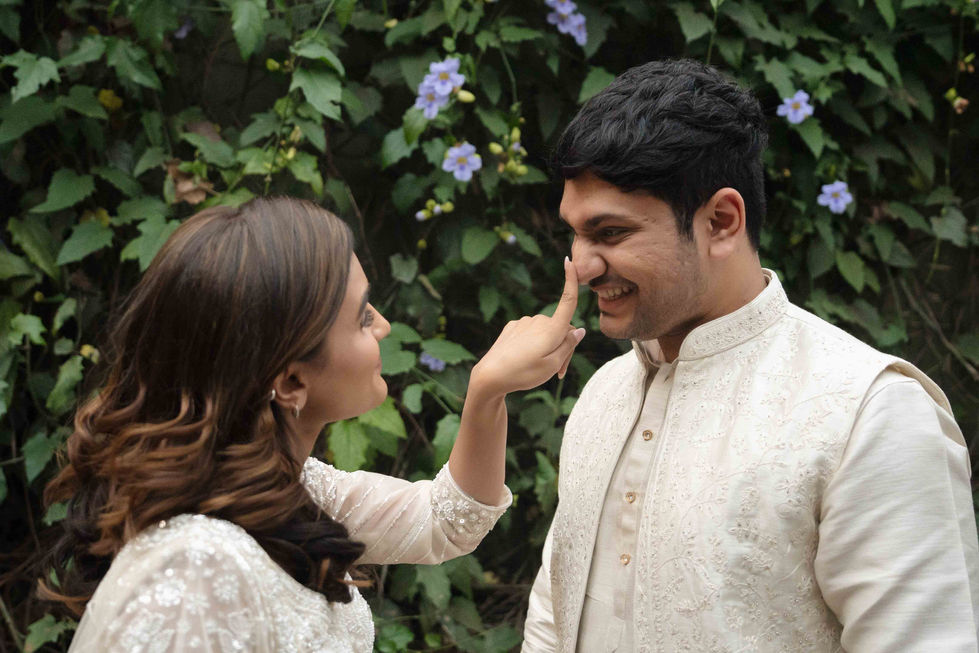 Bride and groom playfully interacting in a garden setting.