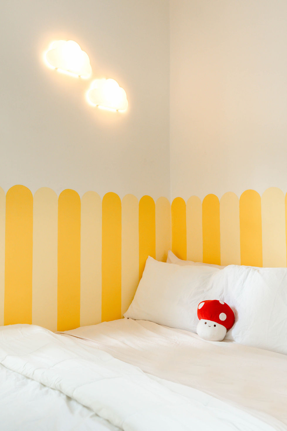 Room with yellow stripes and mushroom pillow.