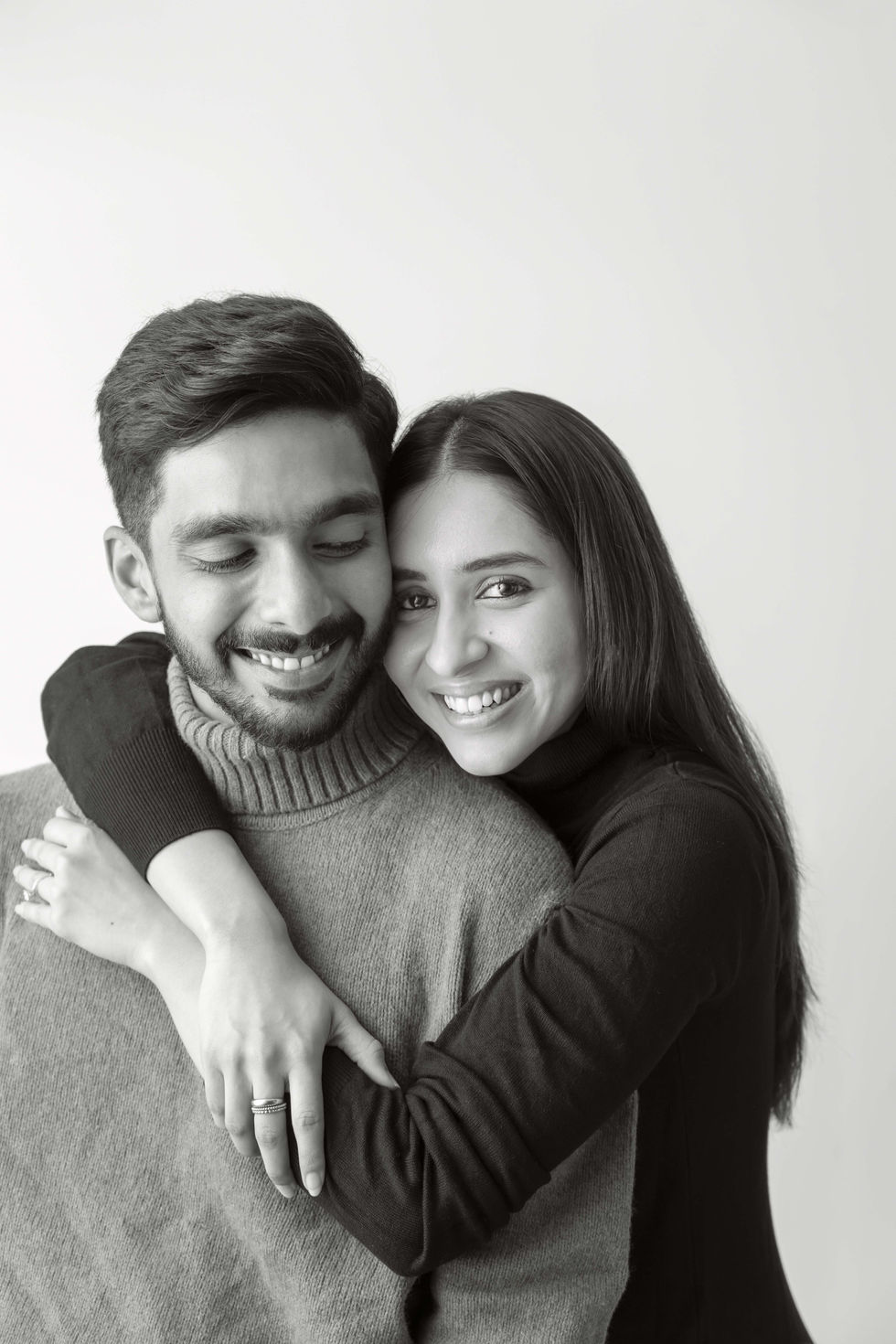 Smiling couple embracing in black and white photo.