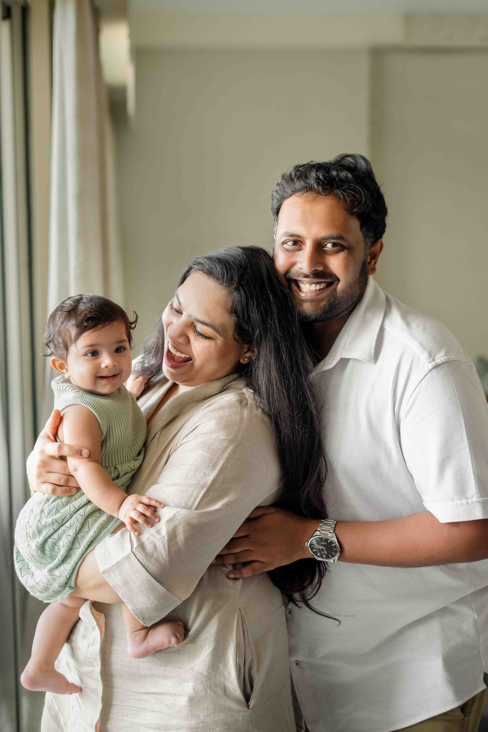 Smiling family with a baby in cozy setting.