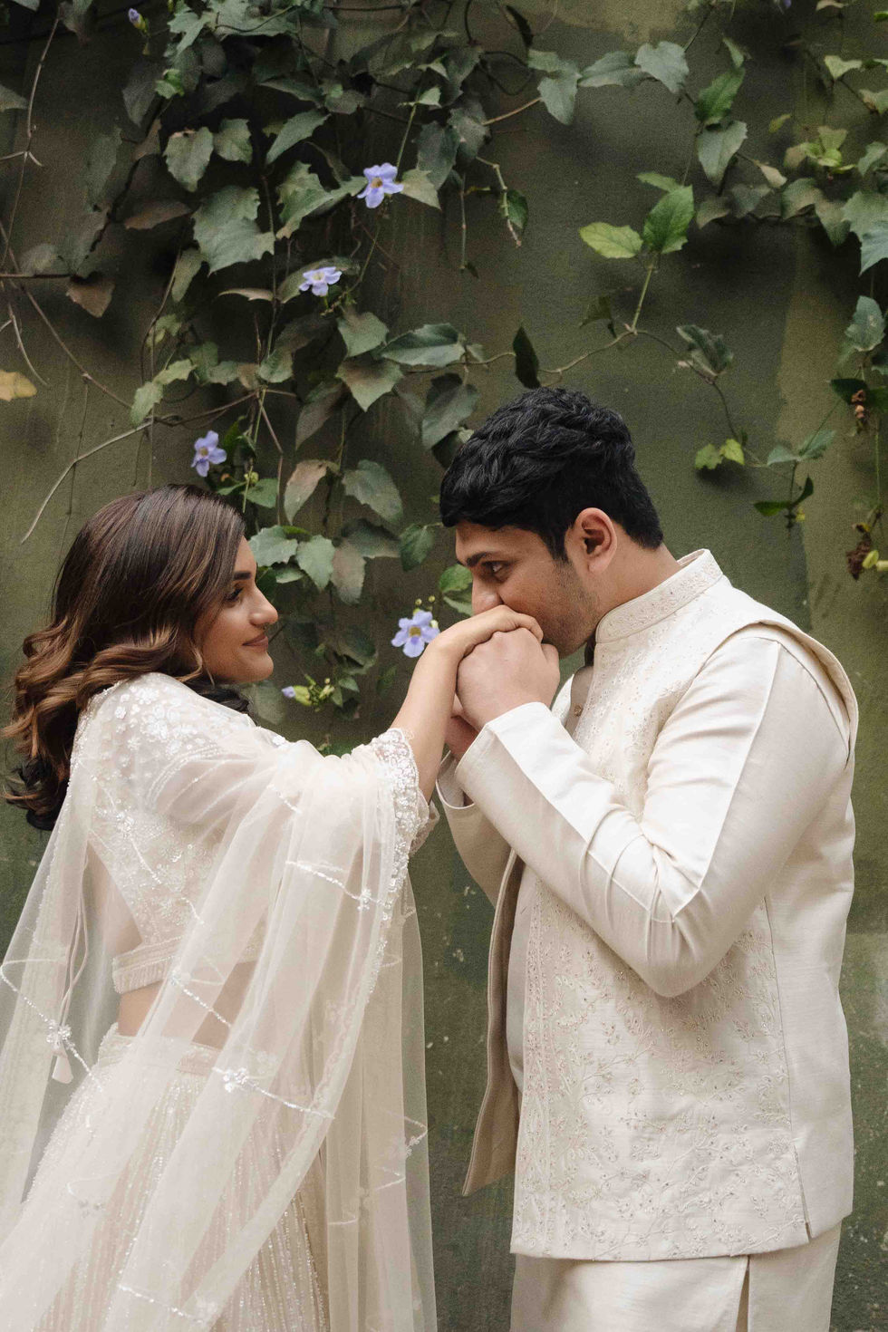 Bride and groom in traditional attire with floral background.