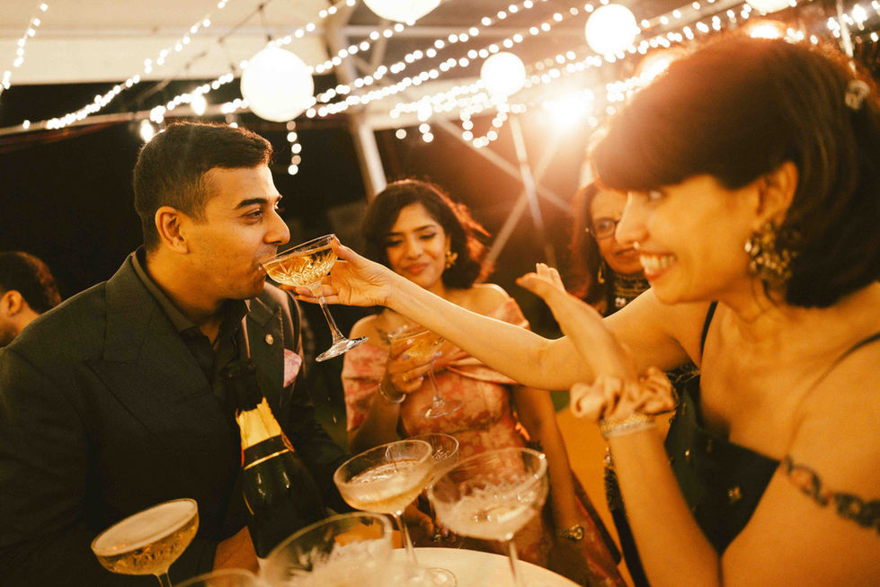 People celebrating with drinks under string lights.