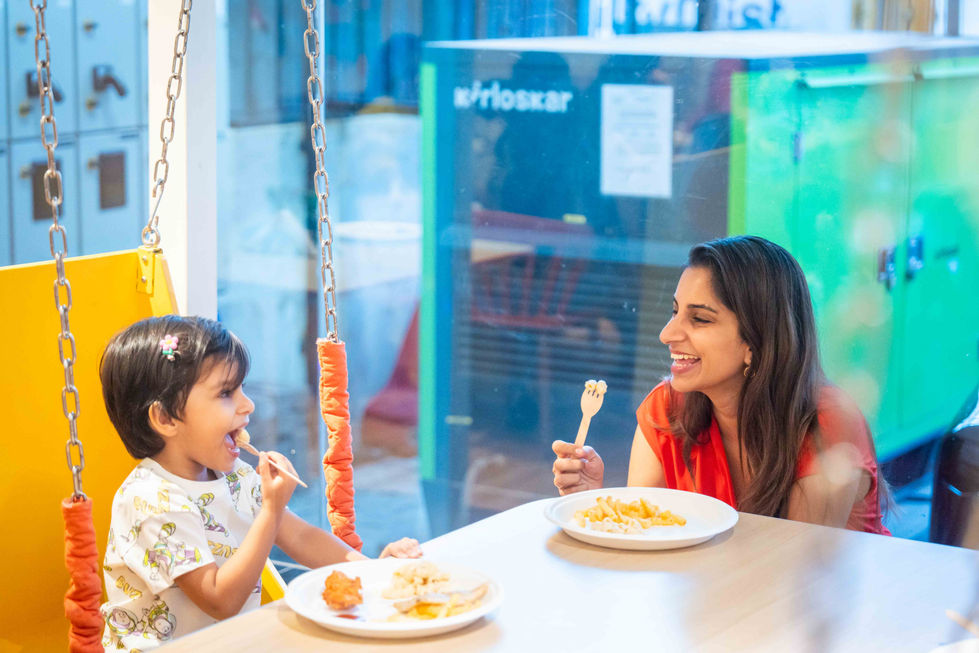 Child and adult enjoying a meal together indoors.