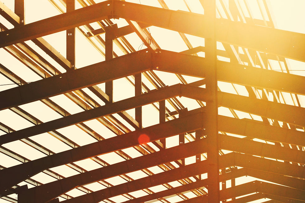 A texas sunset pouring through the steel beams of a commercial roof under construction.