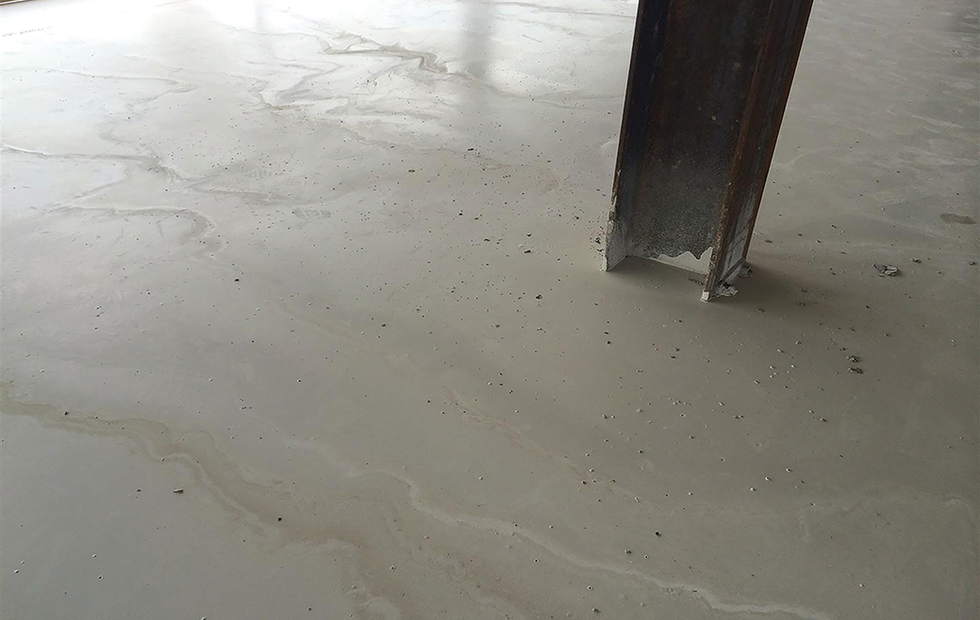 Close-up of a smooth, light-colored concrete floor with metal leg SGBSIntl