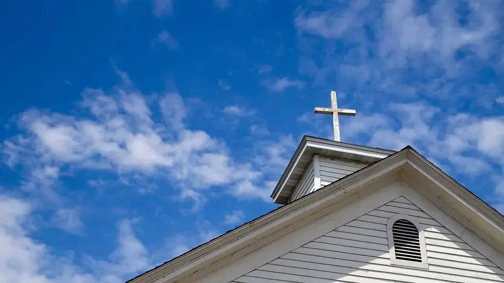 Wooden cross on a simple steeple set against a sunny summer blue sky.