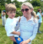 A parent holding a young student at an outdoor Bridges Academy community event.