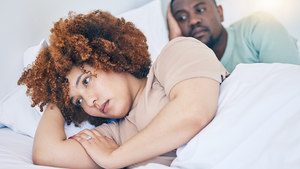 A couple lying in bed, facing away from each other, deep in thought, reflecting a desire mismatch and emotional distance.