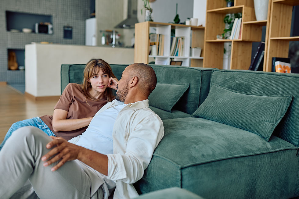 A couple engages in a meaningful conversation about intimacy, seated comfortably on their living room sofa.
