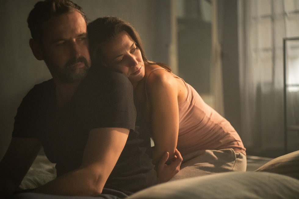 A loving couple sitting on a bed comforting each other as they deal with shame