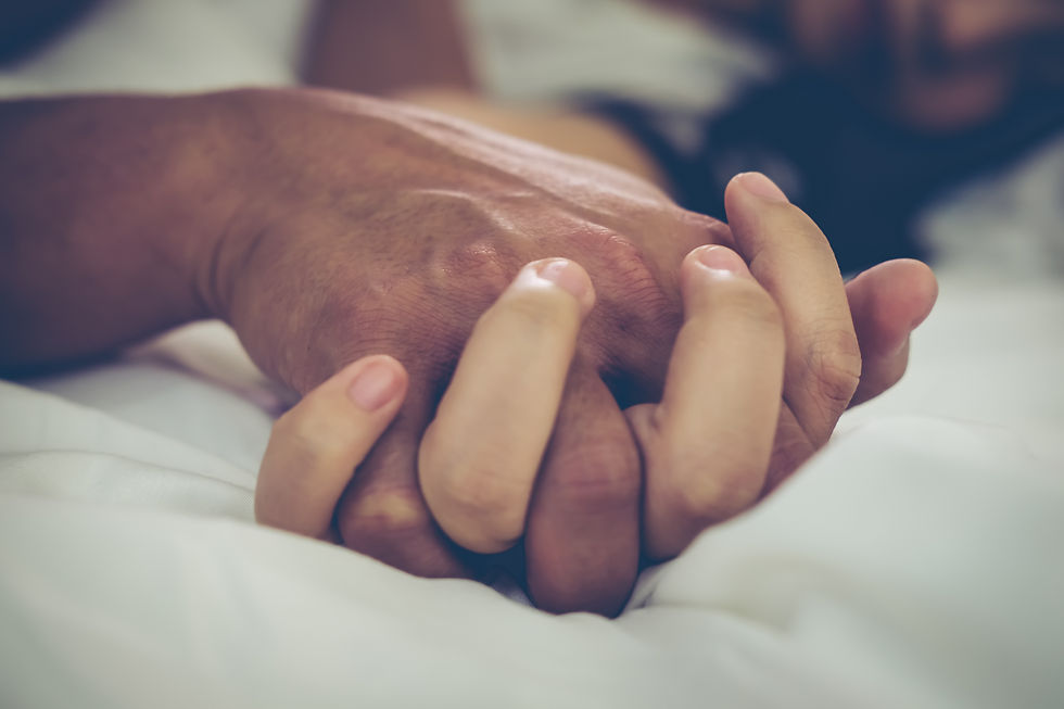 A tender moment captured as a couple holds hands in the warmth of their bed.