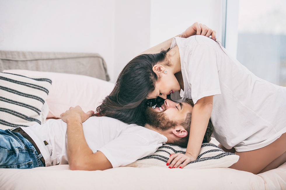 A young couple shares a tender and affectionate moment together in bed, their smiles full of warmth and happiness.