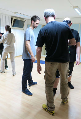 Zwei Teilnehmer üben gemeinsam Qigong-Partnerübungen in einer Trainingshalle in Luzern.