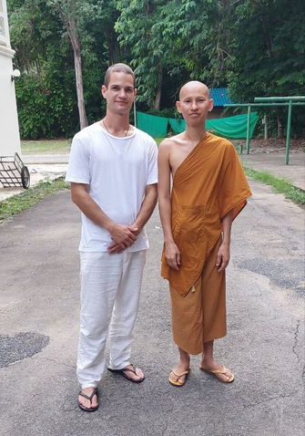 Zwei Männer, darunter ein buddhistischer Mönch, stehen zusammen und lächeln.