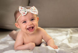 Ein Baby was in die Kamera lächelt Babyfoto KölnBabyfotoshootinginköln
