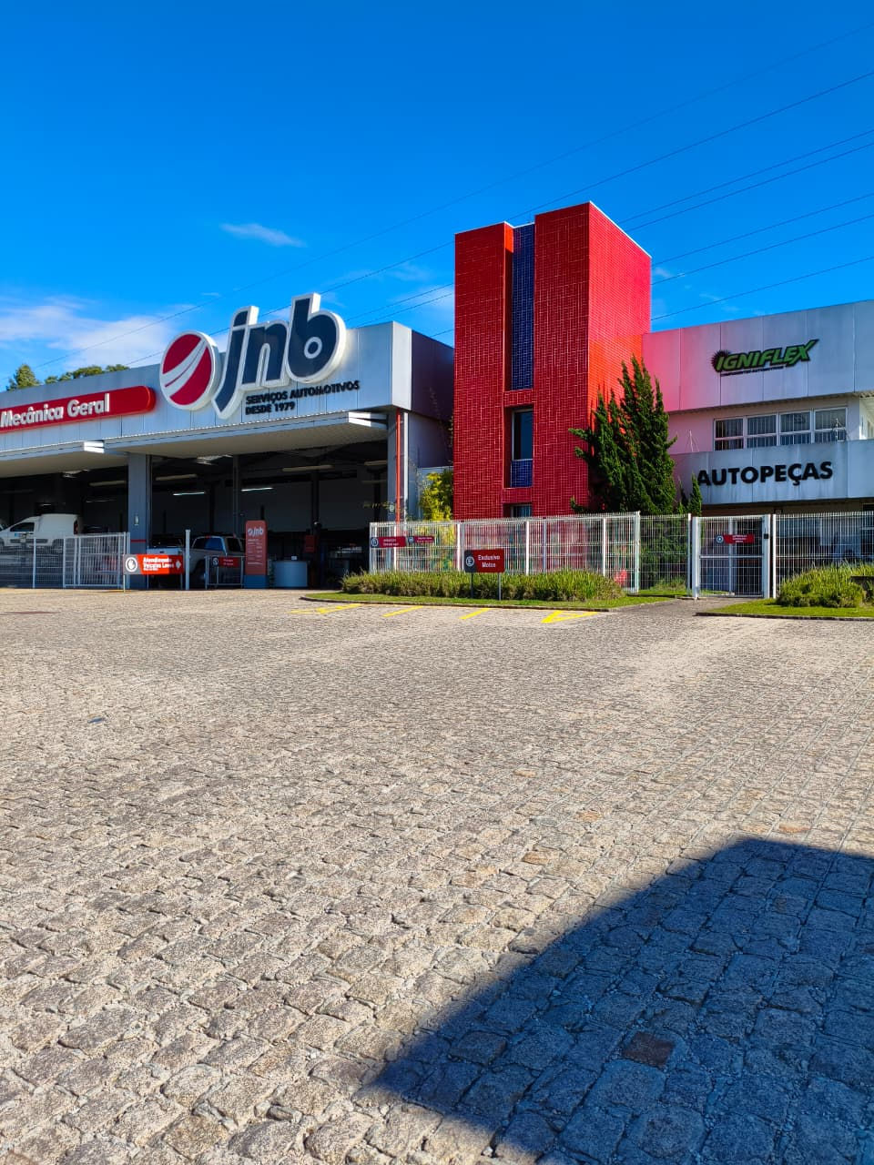 Fachada da sede do Grupo JNB sob céu azul claro.