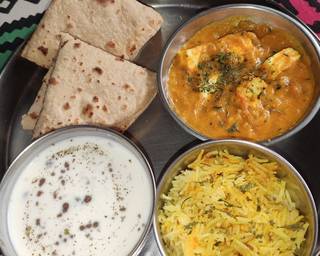 Paneer Butter Masala served with pulao, raita and 2 chapatis in a thalo