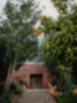 Traditional Moroccan retreat entrance surrounded by lush greenery, offering a peaceful and private sanctuary for guests.