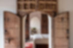 Rustic Moroccan doorway opening into a luxurious retreat bedroom, blending traditional design with modern comfort.
