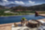 Infinity pool overlooking the lush greenery and red cliffs of the Atlas Mountains, paired with traditional Moroccan decor and tea service for ultimate relaxation during the retreat.