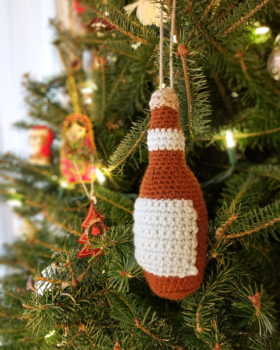 Un ornement au crochet en forme de bouteille de bière est placé dans un sapin de Noël