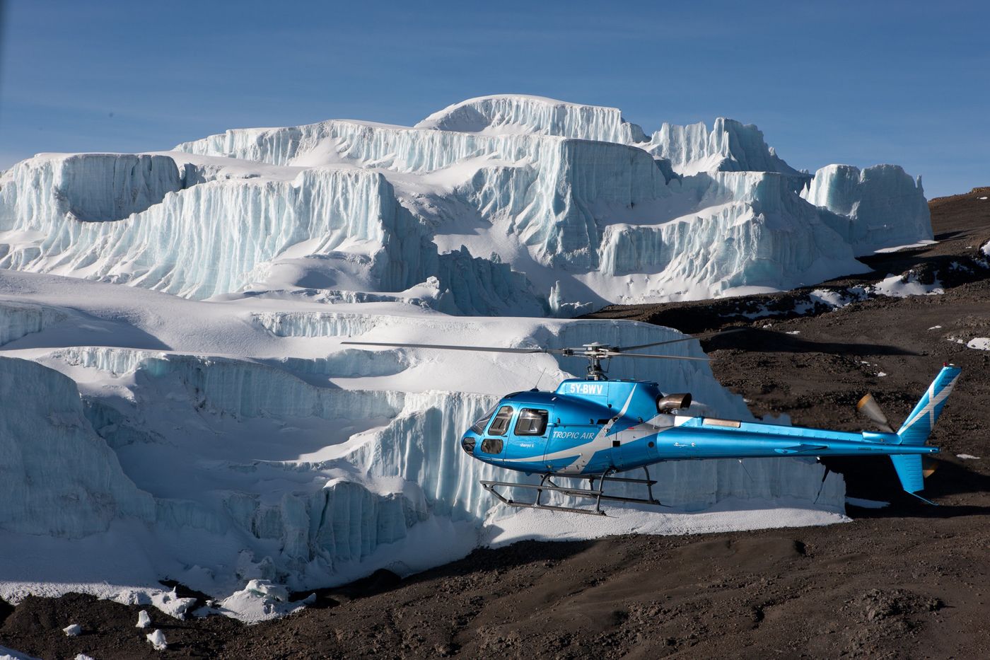Helicopter landed beside towering glacier ice