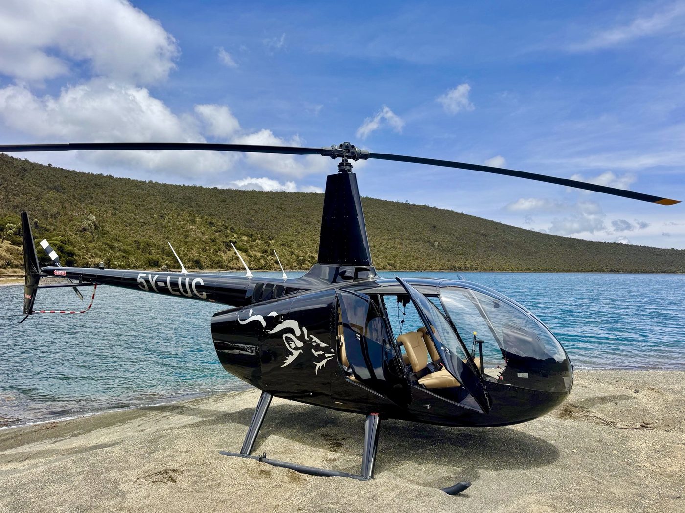 Black Robinson R66 of a local Kenyan operator landed on the beach of a mountain lake