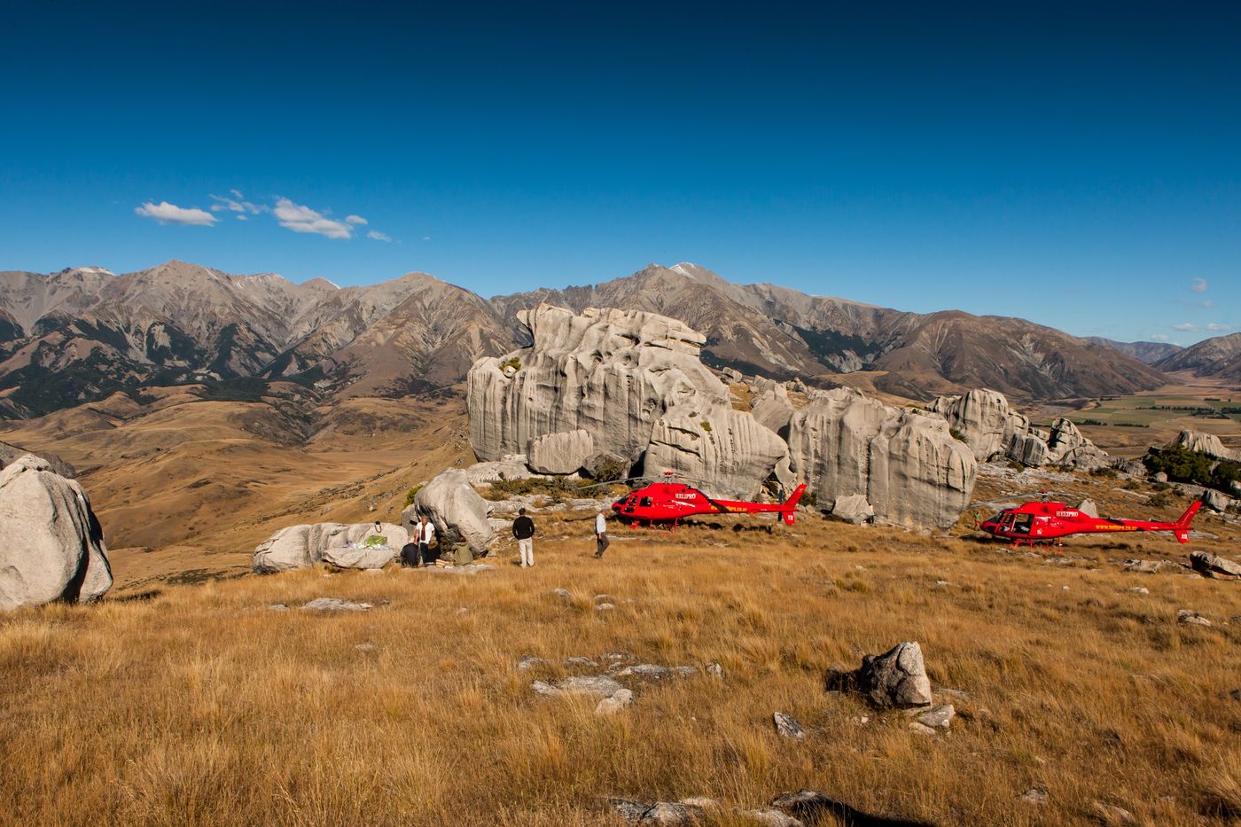 Two red helicopters among limestone boulders at Castle Hill, New Zealand